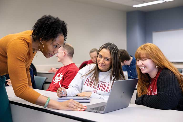 Three women peer at laptop computer