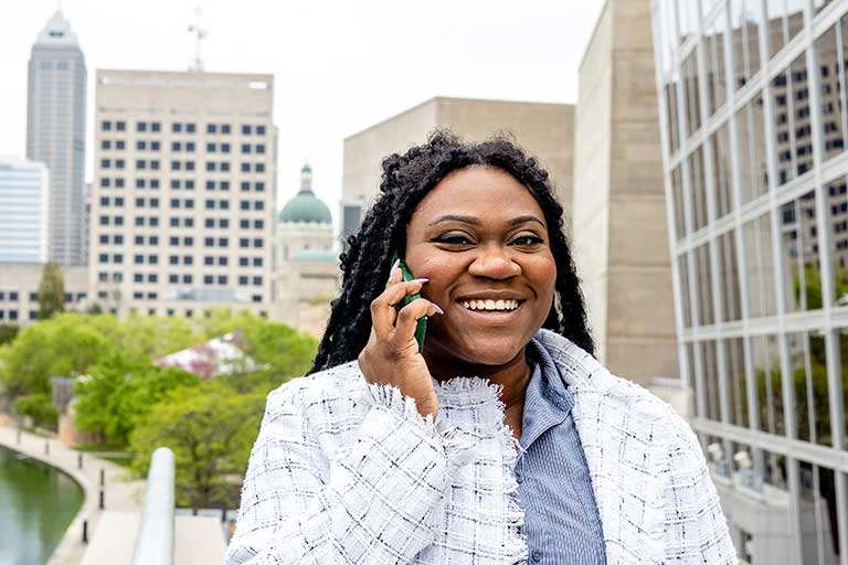 Student talks on phone outside with Indianapolis in the background